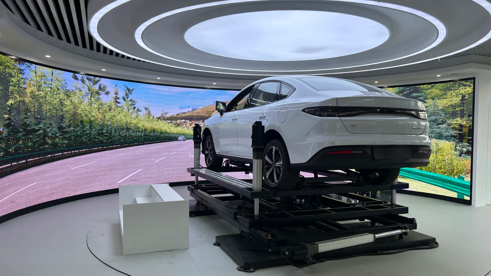 Application photo of the seven-actuator platform carrying a vehicle with surround visual screens; the vehicle and screens are not supplied with the platform